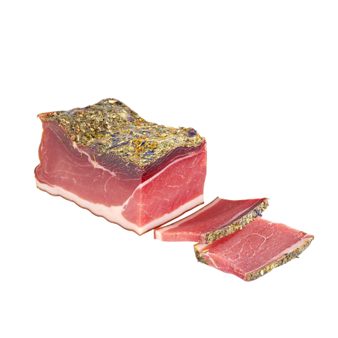 Kräuterspeck mit bunter Blütenkruste, freigestellt auf Weiß, zwei dünne Scheiben daneben