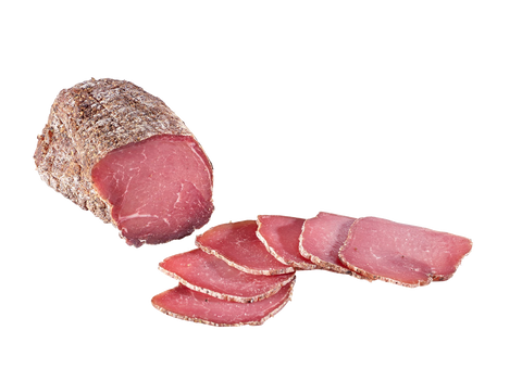 Schinkenspeck am Stück mit rötlichem Anschnitt und aufgefächerten Scheiben vor weißem Grund