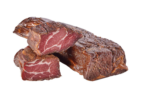 Zwei Stück Knoblauchspeck mit dunkler Rinde und weiß durchzogener Schnittfläche vor Weiß