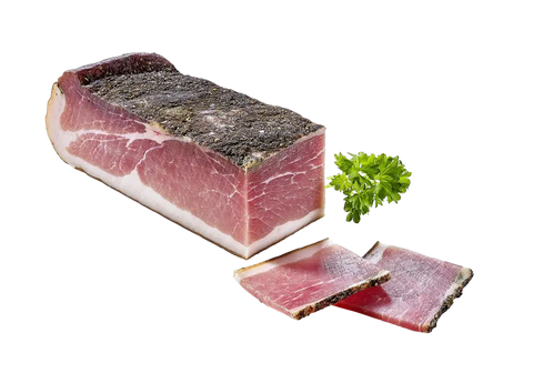 Block luftgetrockneter Speck mit dunkler Gewürzkruste, daneben zwei Scheiben und frische Petersilie.