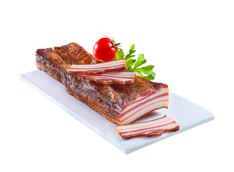 Geräucherter Brettlspeck auf heller Platte, angeschnitten, mit Tomate und Petersilie garniert